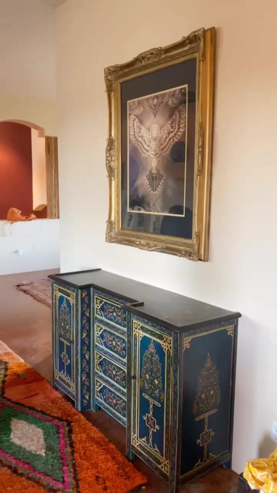 Interior of the Joshua Tree Airbnb: Moroccan living room with a hand-painted blue cabinet, gold-framed art, and Berber rugs
