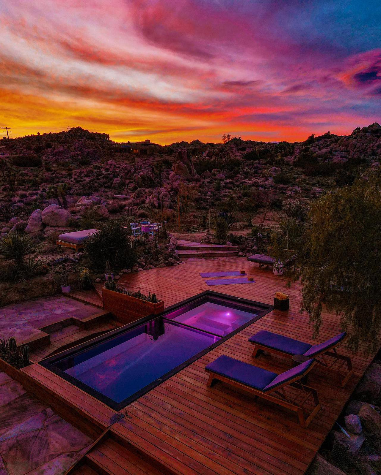 Private heated pool and hot tub deck at Boulder Horizons under a vivid pink and orange Joshua Tree sunset