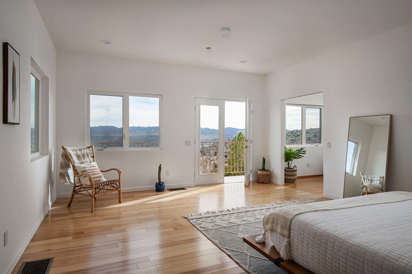 Interior of the Infinite Horizon Joshua Tree rental: light-filled bedroom with hardwood floors, French doors, and panoramic desert views
