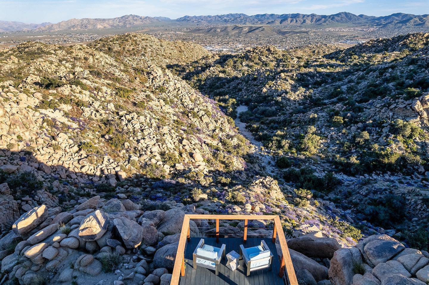 Cliff-edge viewing deck with lounge chairs above a canyon of boulders