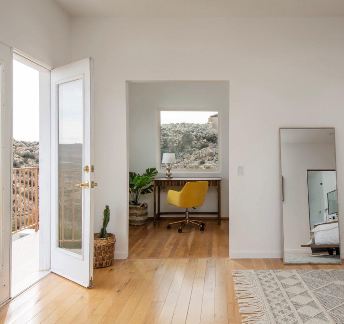 Interior of the Joshua Tree Airbnb: home office nook with a desk and window framing the boulder-strewn desert